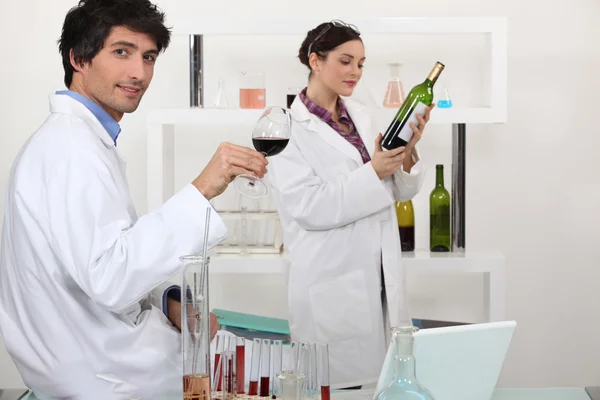 Férfi és nő bor vizsgálata laboratóriumi tudomány — Stock Fotó