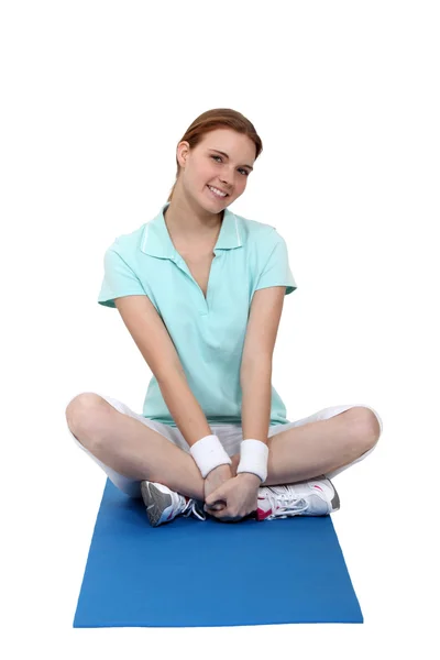 Mujer sentada en una alfombra de ejercicio — Foto de Stock