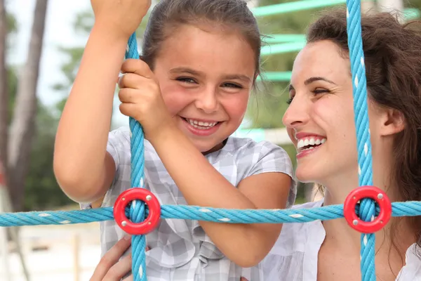 Uma menina e sua mãe brincando em um playground — Fotografia de Stock