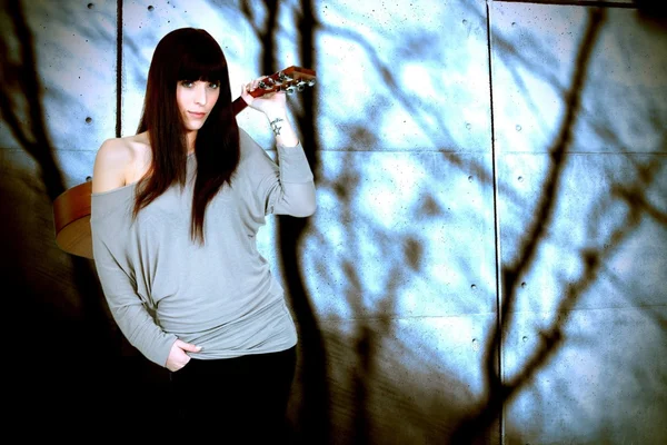 stock image Portrait of brunette carrying guitar on her back