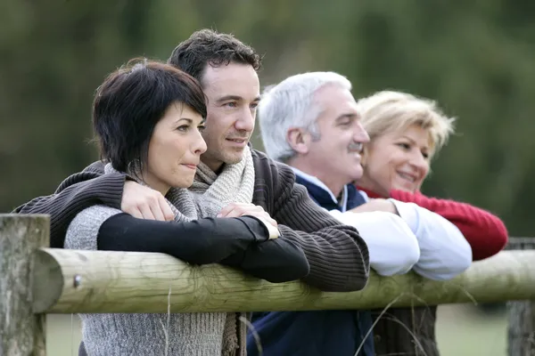 Two couples leaning on a countryside fence Stock Picture