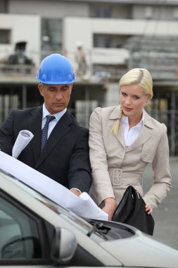 An ambitious team of engineers consulting a drawing on a car's windscr clipart