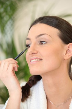 Woman applying eyeliner clipart