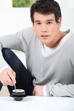 Young man having a cup of coffee clipart