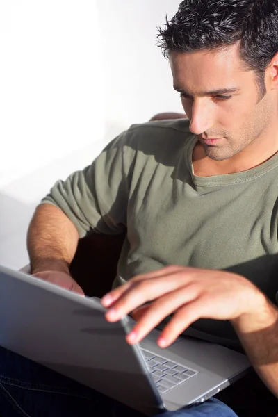 Uomo dai capelli scuri seduto con computer portatile — Foto Stock