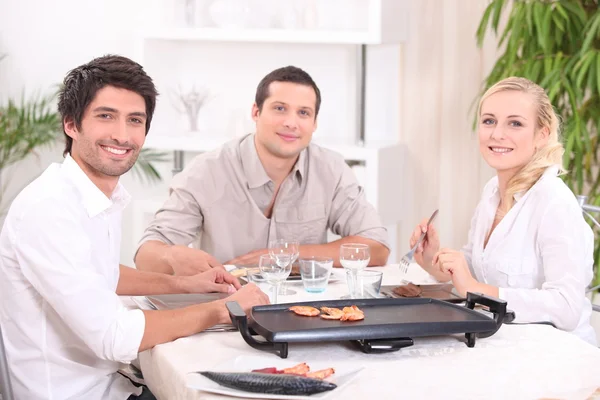 Friends cooking dinner on a tabletop hot plate — Stock Photo, Image