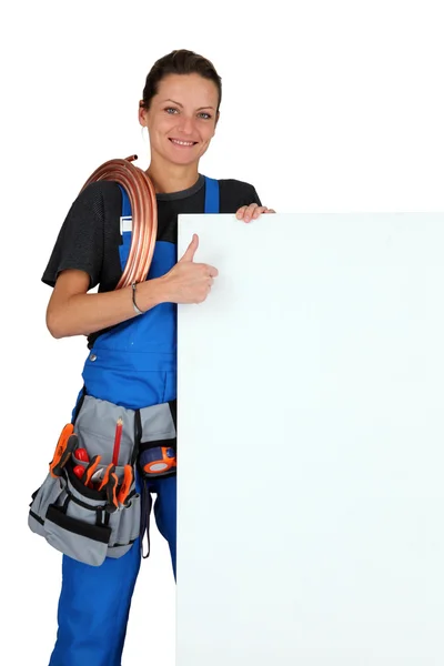 Encanador fêmea com uma placa deixada em branco para sua mensagem — Fotografia de Stock