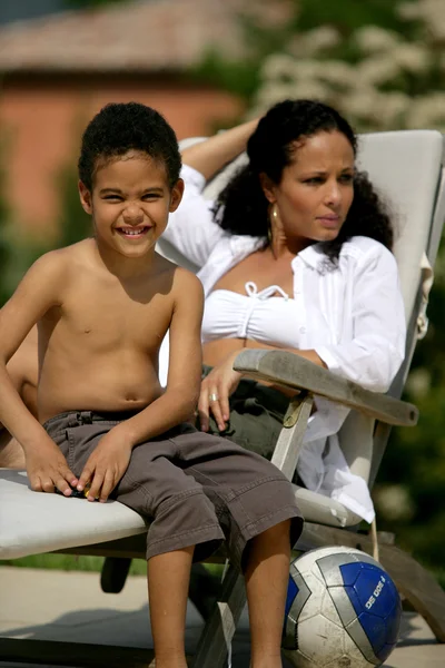 Mulher e menino sorridente em uma cadeira de praia — Fotografia de Stock