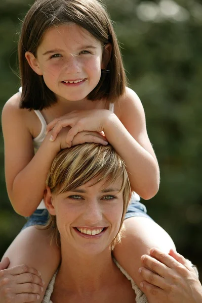 그녀의 어머니의 어깨에 타고 어린 아이 — 스톡 사진