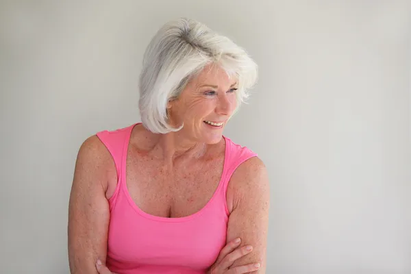 Señora de pelo gris posando por la pared — Foto de Stock