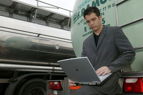 Használata a laptop, miközben a teherautó támaszkodva üzletember — Stock Fotó