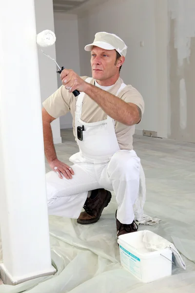Décorateur peignant une pièce blanche avec un rouleau — Photo