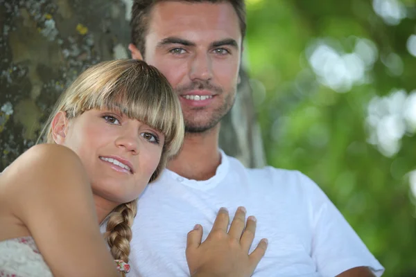 Pareja sentada junto al árbol en el parque — Foto de Stock