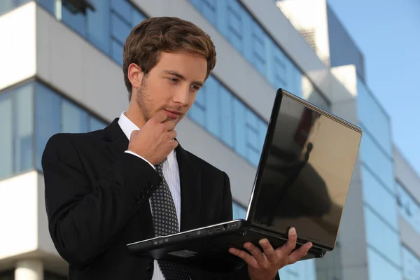 Bonito homem de negócios usando um laptop na cidade — Fotografia de Stock