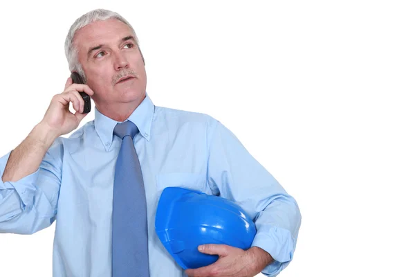 Middle-aged foreman making a call hard hat in hand — Stock Photo, Image