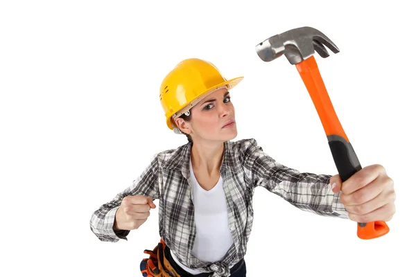 En arg kvinna byggnadsarbetare med en hammare. — Stockfoto