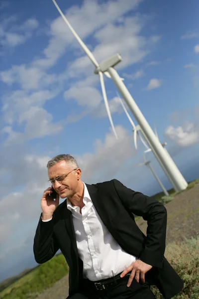 Человек, использующий свой мобильный телефон рядом с ветряными турбинами — стоковое фото