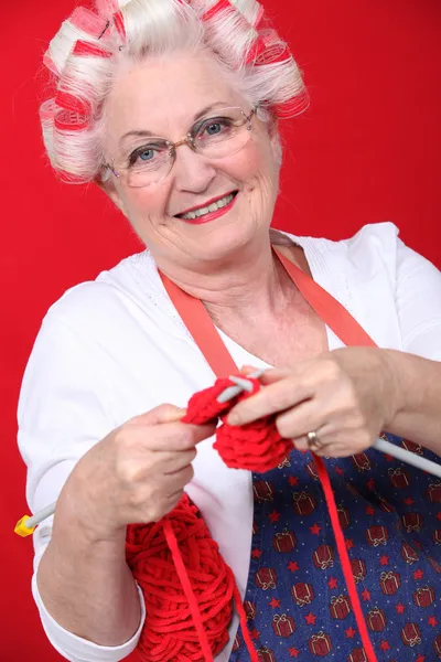 Granny with her hair in rollers and knitting — Stock Photo, Image