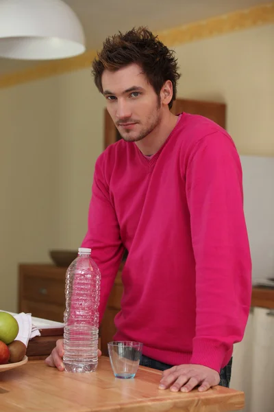 Homem na cozinha servindo copo de água — Fotografia de Stock