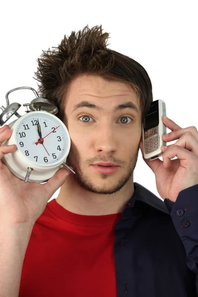 Hombre con reloj despertador y teléfono móvil — Foto de Stock