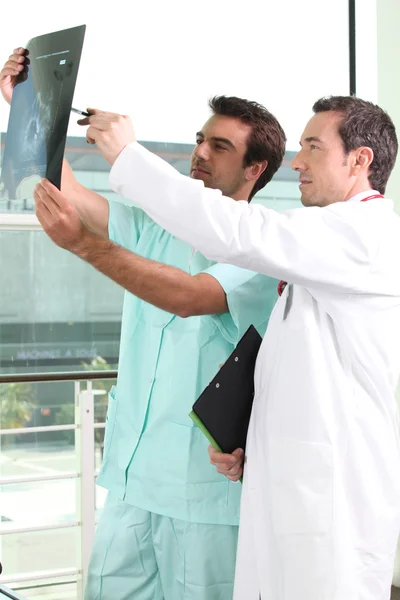 Dos doctores varones mirando una imagen de rayos X —  Fotos de Stock