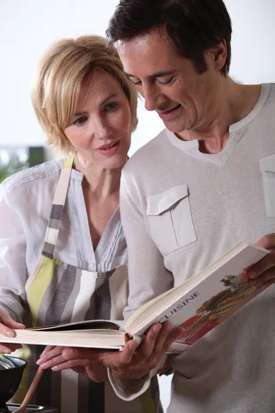 Couple looking at cookery book — Stock Photo, Image