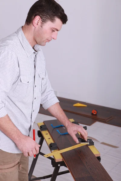 Чоловік вимірює дошку деревини — стокове фото