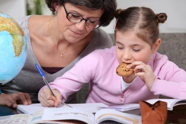 Woman helping her granddaughter with her homework clipart