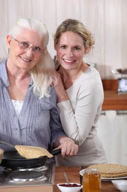 Mother and daughter cooking crepes together clipart