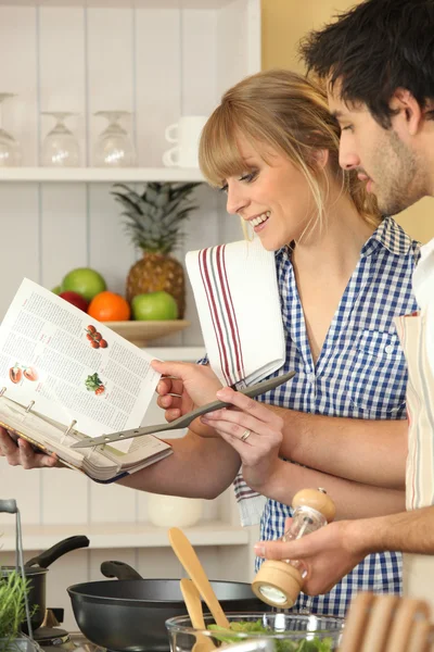 Young couple using a cookbook — Stock Photo, Image