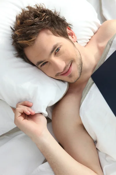 Молодой человек улыбается в постели — стоковое фото