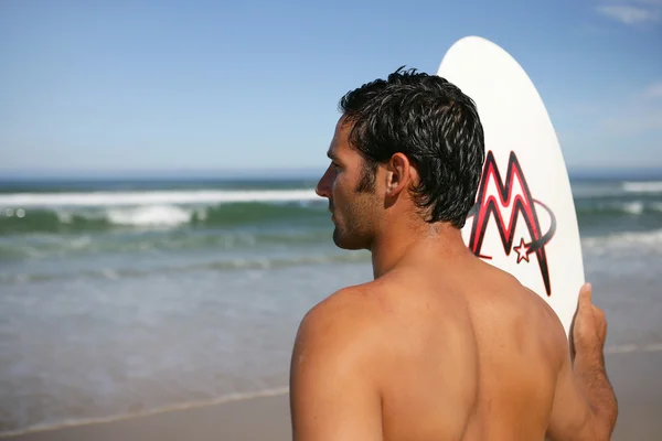 Homem com uma prancha de surf a olhar para o oceano — Fotografia de Stock