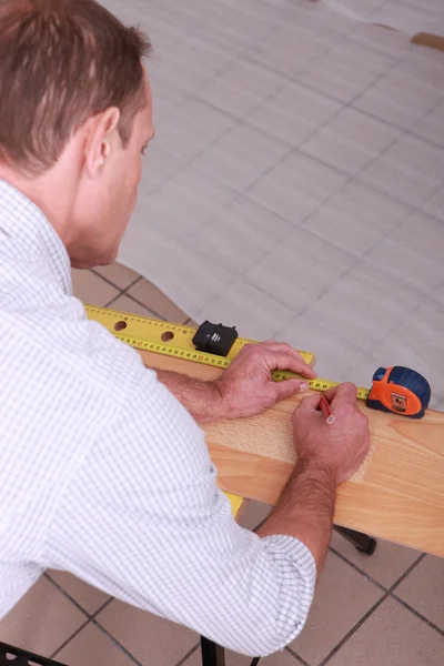 Trabalhador marcando uma medição em uma prancha de madeira — Fotografia de Stock