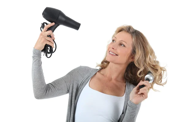 Mulher de cabelos longos usando um secador de cabelo e grande escova redonda — Fotografia de Stock