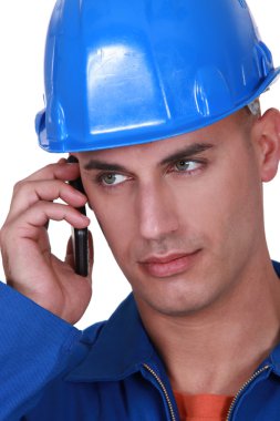 Tradesman talking on his mobile phone clipart