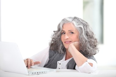 Mature grey-haired lady with laptop clipart