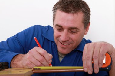 Tradesman marking a measurement on a copper tube clipart