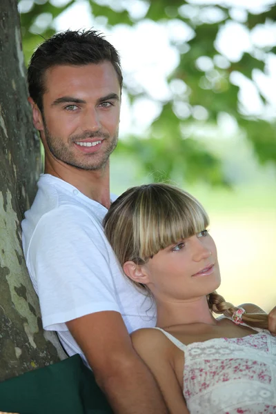 Couple relaxing under a tree — Stock Photo, Image