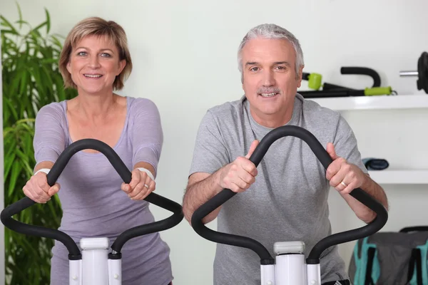 Seniorenpaar fährt Fahrrad in der Turnhalle — Stockfoto