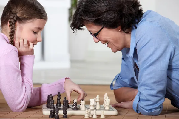 Девушка и ее бабушка играют в шахматы — стоковое фото