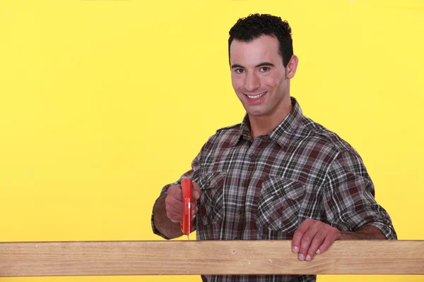 Artesano cortando una tabla de madera con una sierra — Foto de Stock