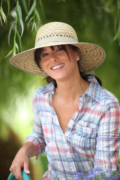 Young woman with a straw hat is watering in her kitchen garden — Stock Photo, Image