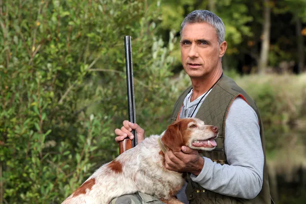 Hunter toma un rifle y acaricia a un perro de caza — Foto de Stock