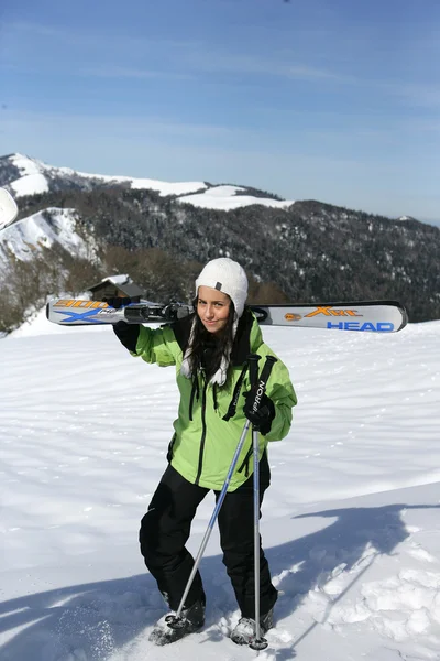 Młoda kobieta, niosąc jej narty — Zdjęcie stockowe