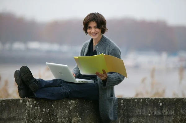 Žena studium, zatímco seděl na zdi — Stock fotografie