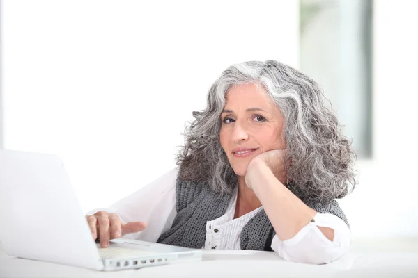 Volwassen grijs-haired dame met laptop — Stockfoto