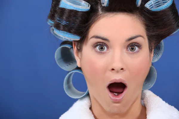 Förvånad kvinna med håret i rullarna — Stockfoto