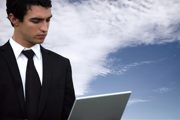 Бизнесмен с ноутбуком на фоне голубого неба — стоковое фото