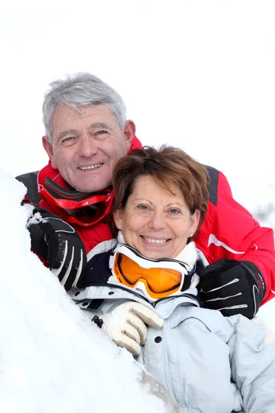 Smiling senior couple laid in snow — Stock Photo, Image