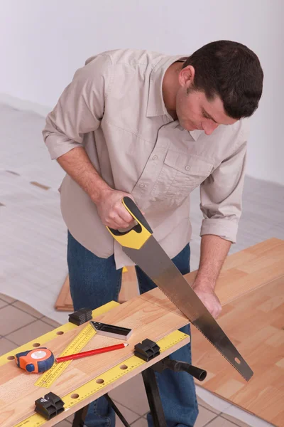 Homem serrar piso laminado — Fotografia de Stock